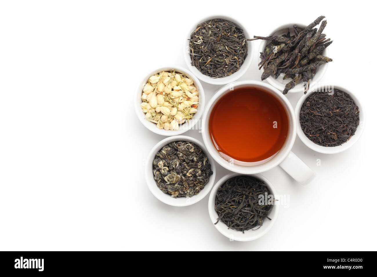 Té negro en blanco taza de té con hojas y flores. Foto de stock
