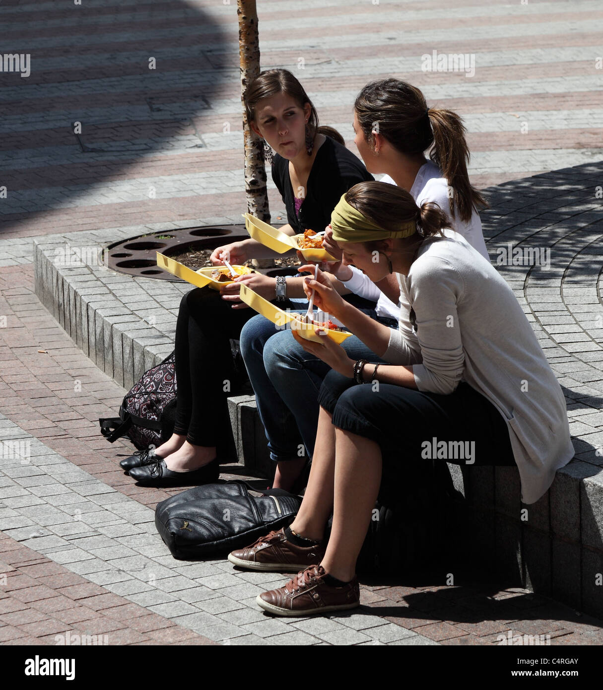 Tres chicas jóvenes comiendo alfresco Cambridge Inglaterra Foto de stock