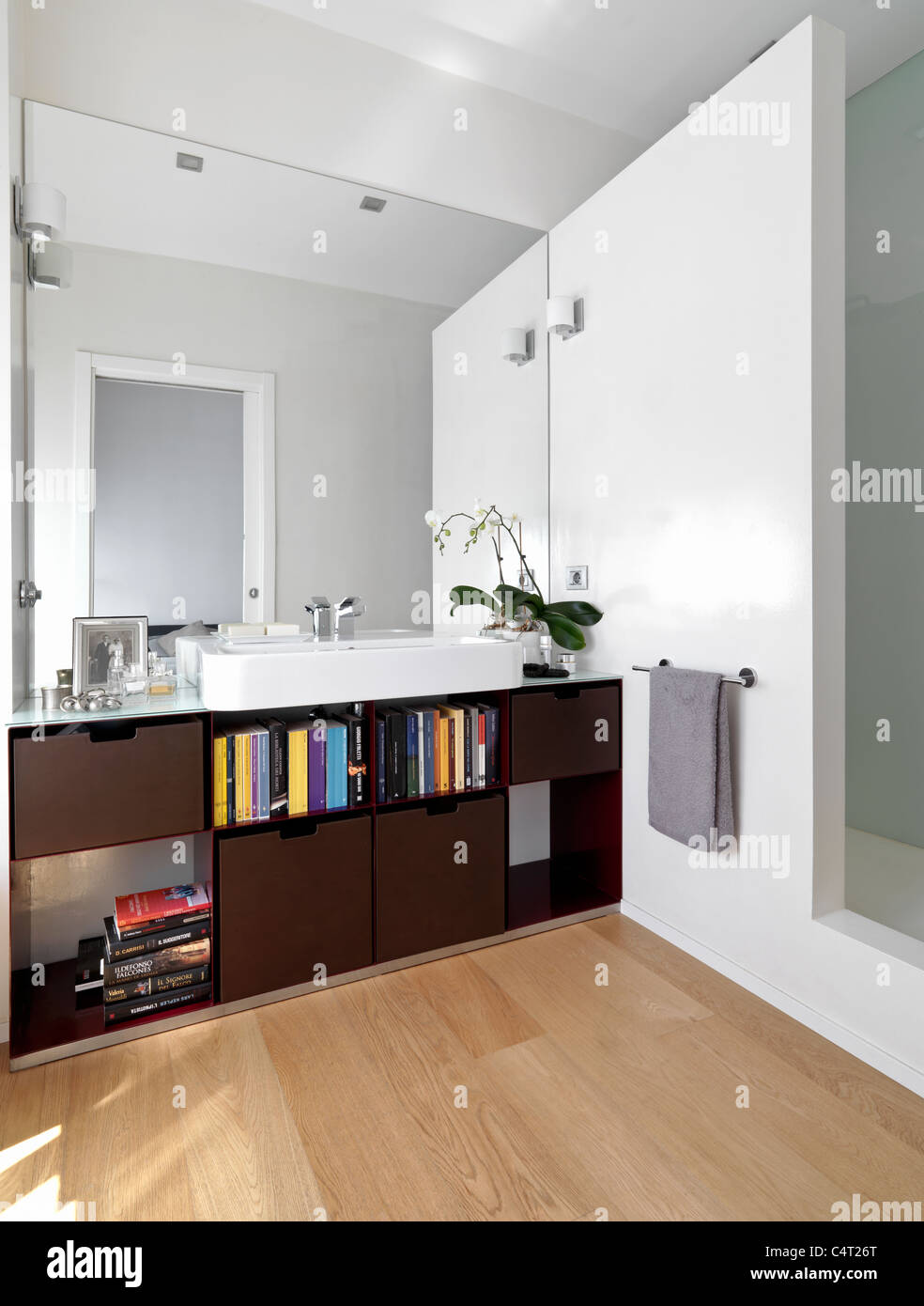 Baño moderno con piso de madera y lavabo blanco Foto de stock