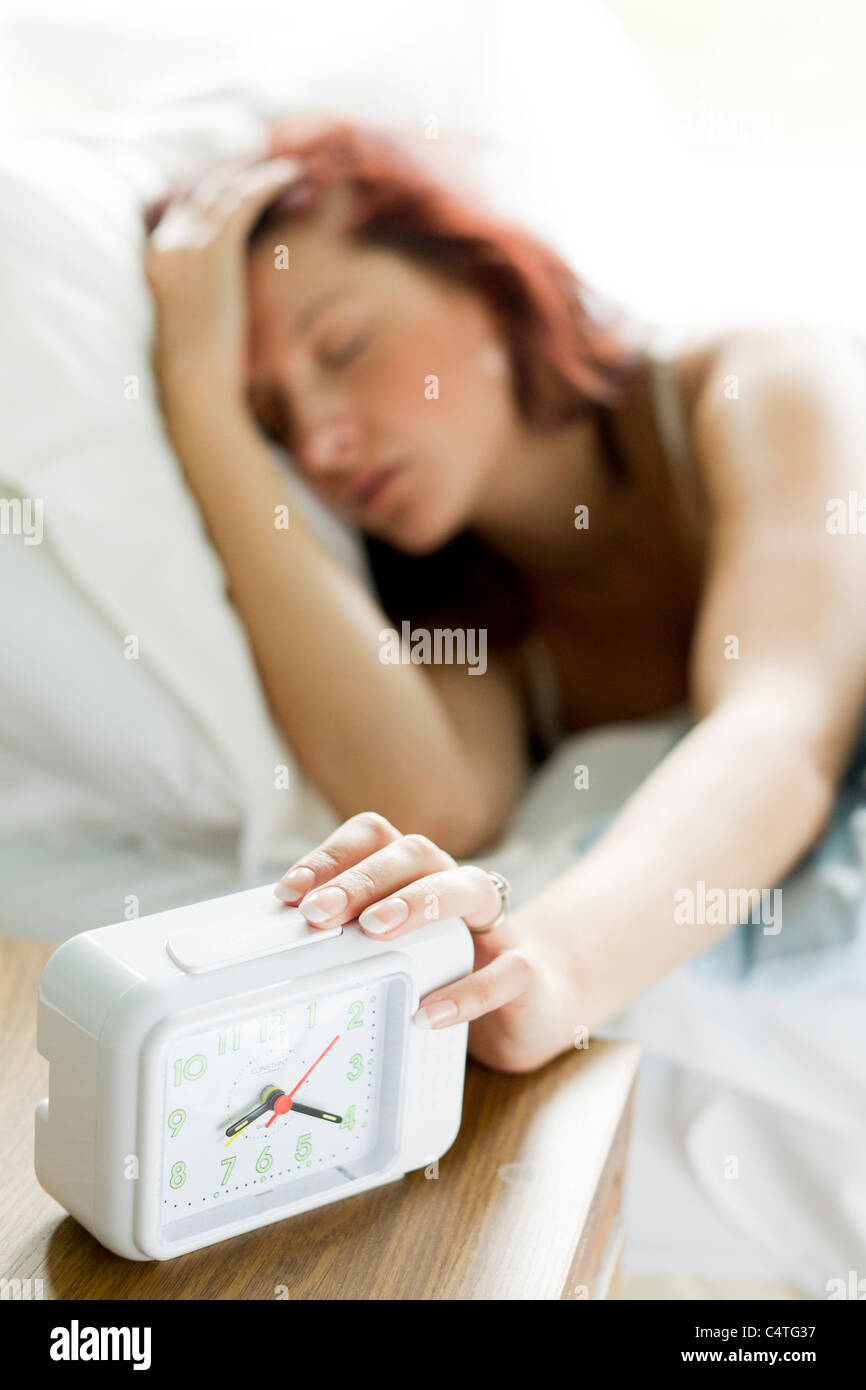 Mujer de apagar el despertador Foto de stock