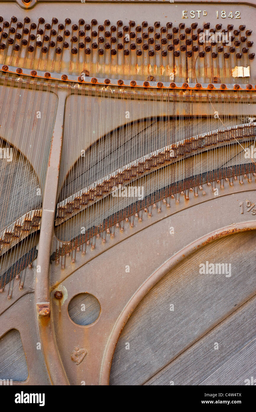 El mecanismo dentro de un viejo piano. Pueden verse los cables corroídos Foto de stock