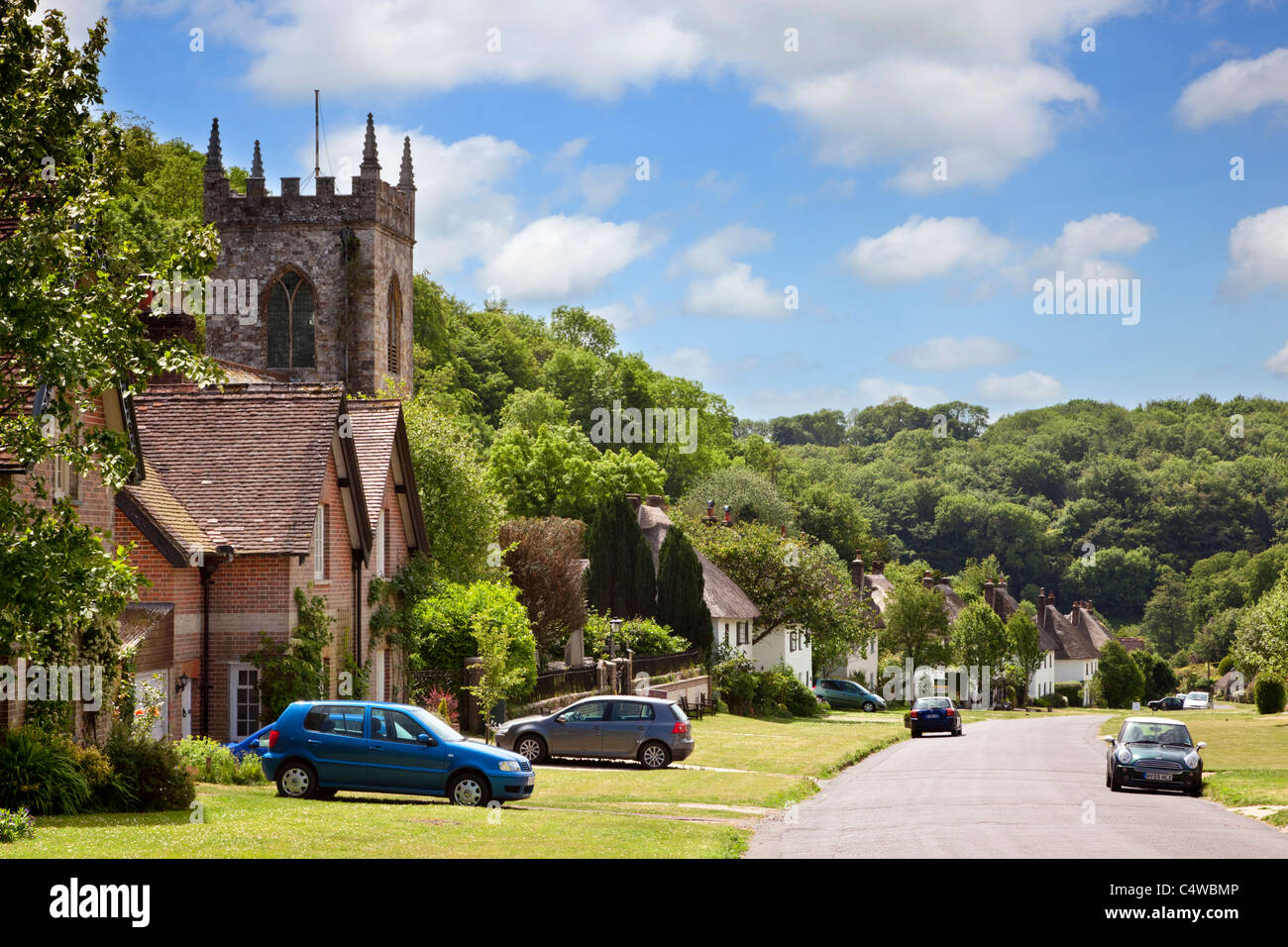 Hermosa villa inglesa de Milton Abbas en Dorset, Inglaterra, Reino Unido, con casitas de campo con tejados de paja y la antigua iglesia del pueblo británico Foto de stock