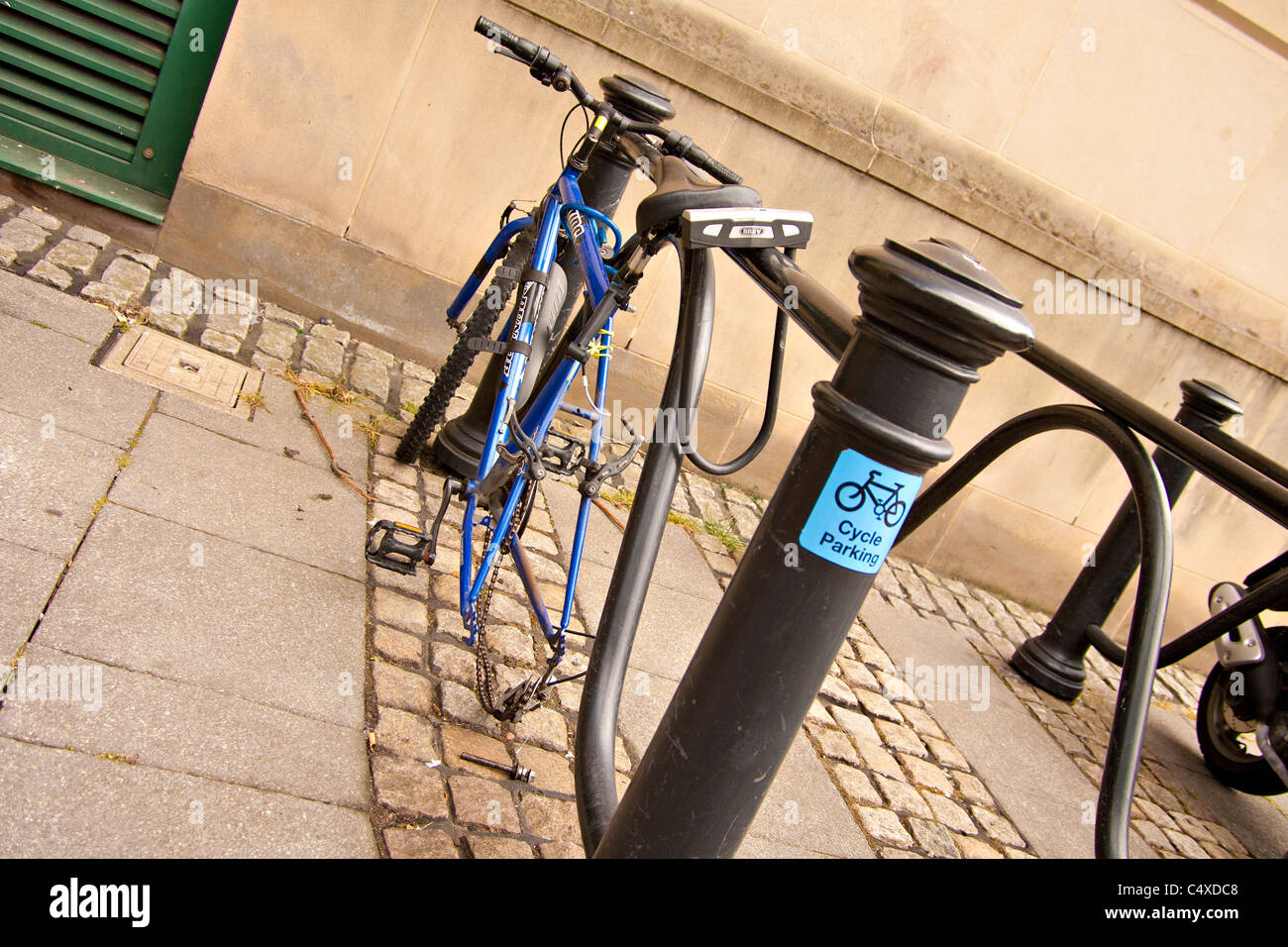 Una bicicleta sin una rueda trasera bloqueada en un ciclo aparcamiento en  Newcastle upon Tyne Fotografía de stock - Alamy