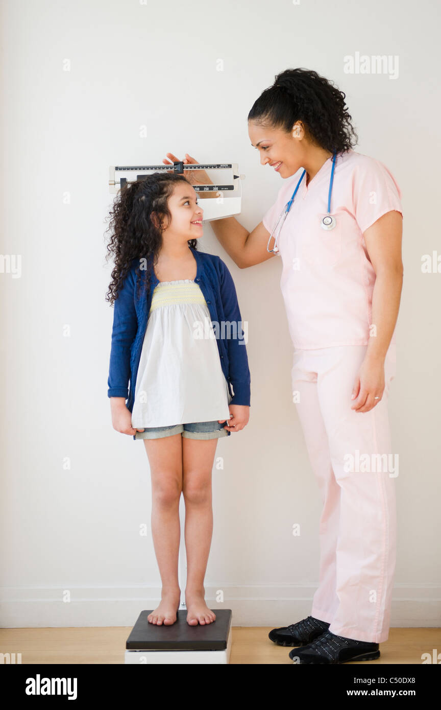 Enfermera chica de pesaje en balanzas Foto de stock