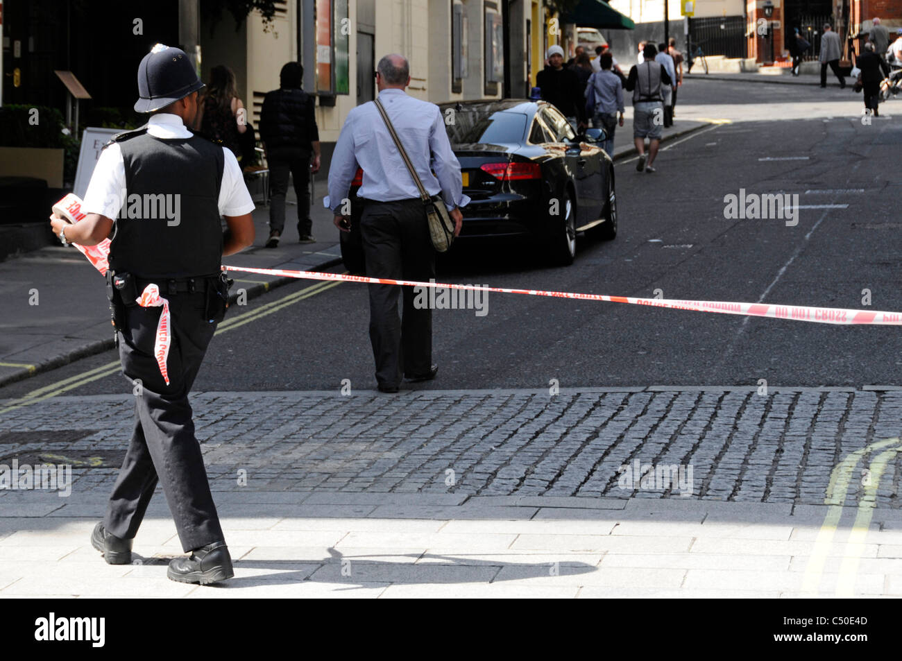 Oficial de policía rolling out CINTA PARA ACORDONAR el acceso a 'The Strand' en Londres debido a incidentes importantes Foto de stock