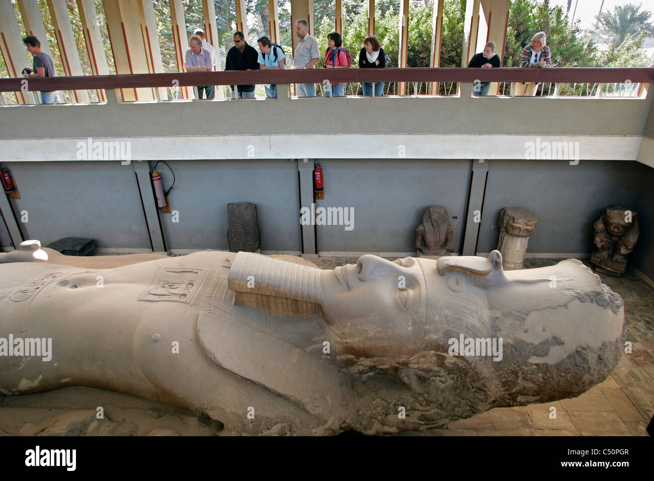 Los turistas ver la colosal estatua de piedra caliza de Rameses II en Memphis, Egipto Foto de stock