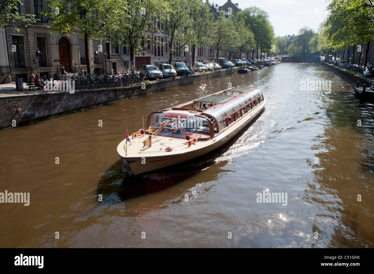 Una barcaza navega hacia abajo un pintoresco canal en la ciudad holandesa de Amsterdam. Foto de stock