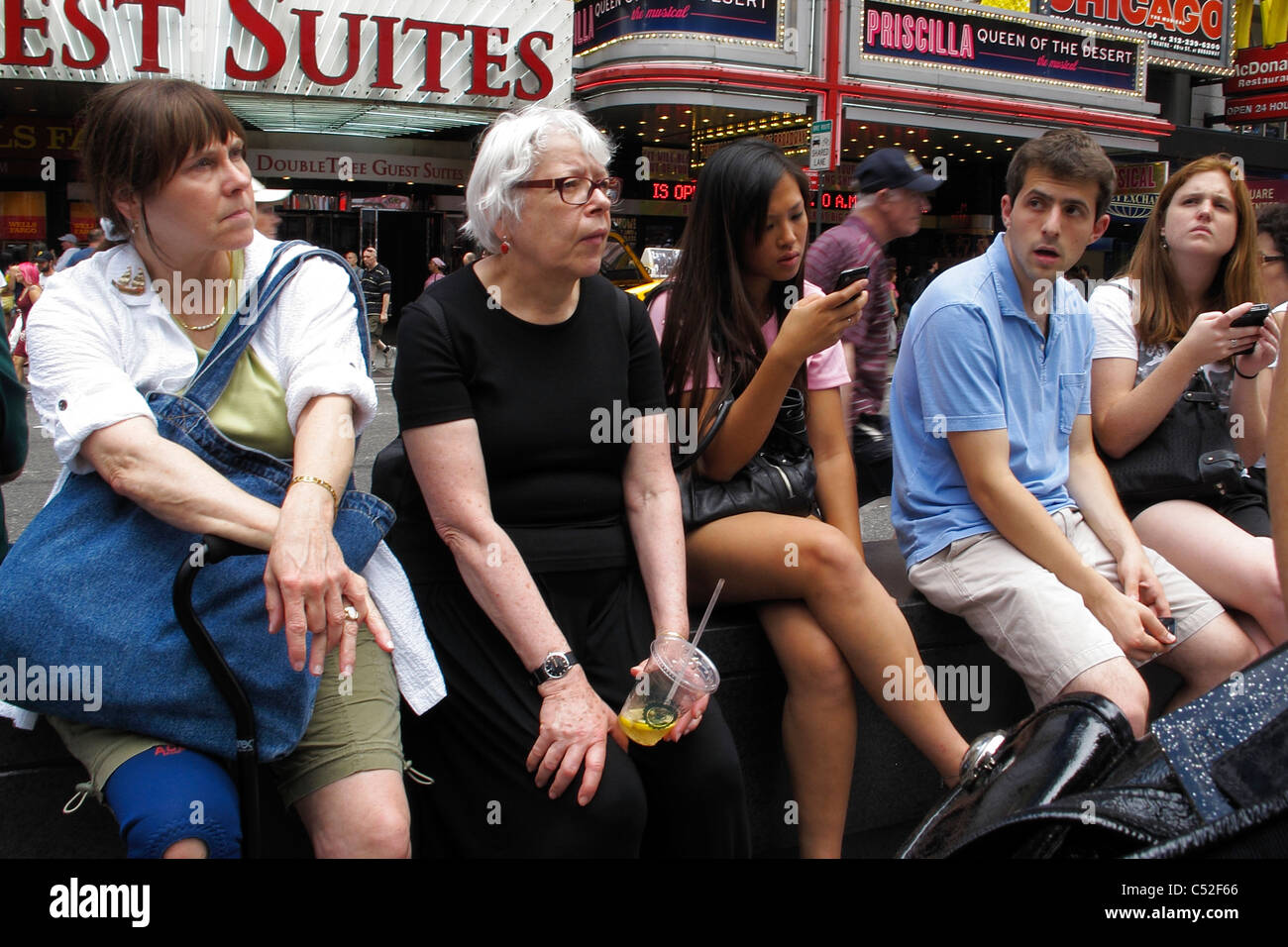Desconectado - Cinco personas se sientan juntos en la plaza de Times Square de Nueva York, inconsciente a cada otros Foto de stock
