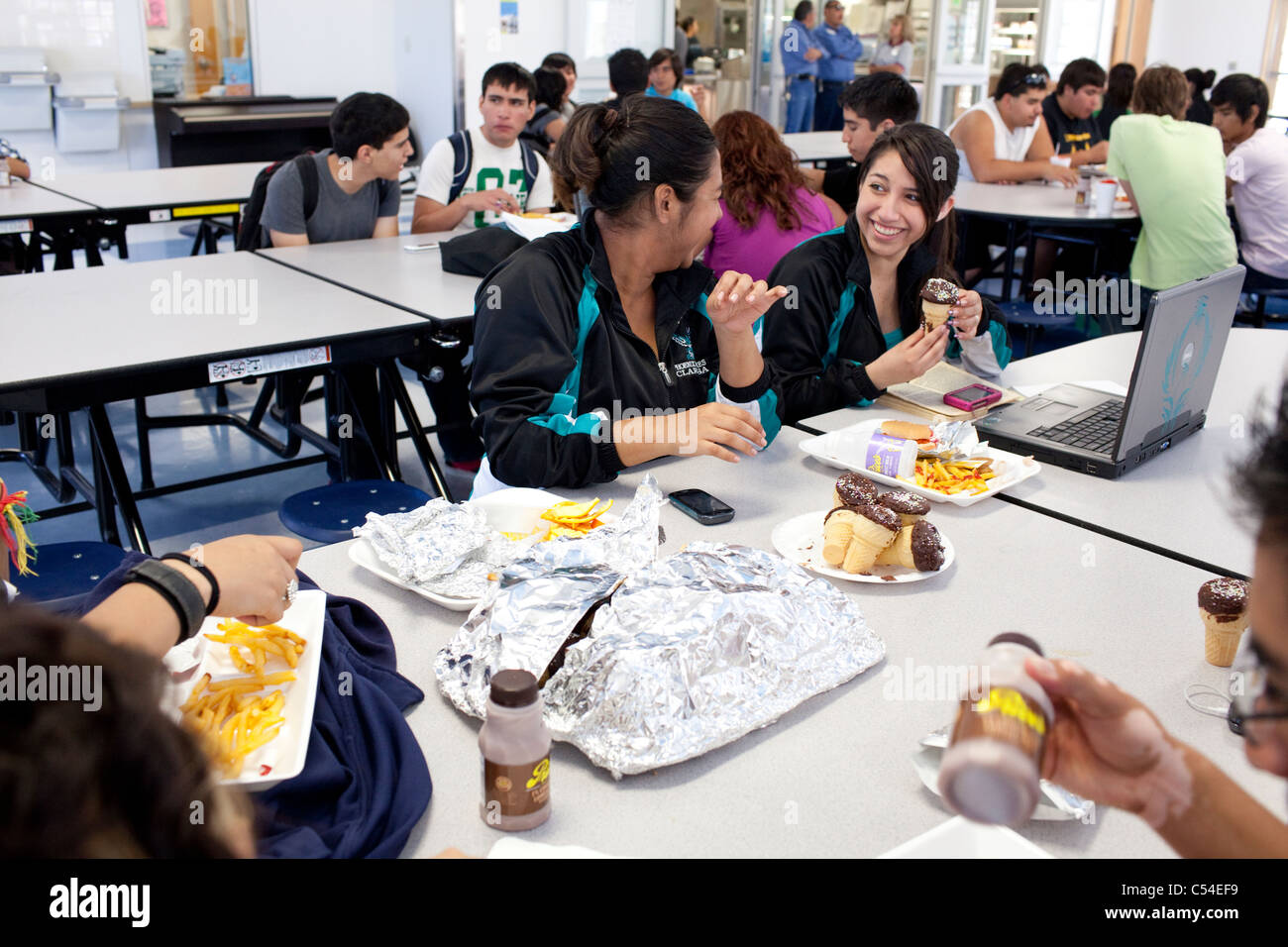 Los estudiantes socializar, utilizar el ordenador portátil y comer el almuerzo en la cafetería de la escuela secundaria en El Paso, Texas Foto de stock