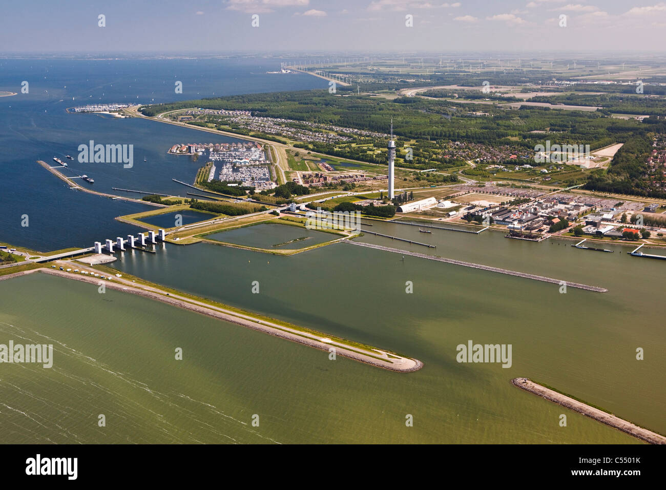 Los Países Bajos Lelystad, vista en presa, cerraduras, marina, torre de televisión y radiodifusión Flevopolder. Antena Foto de stock