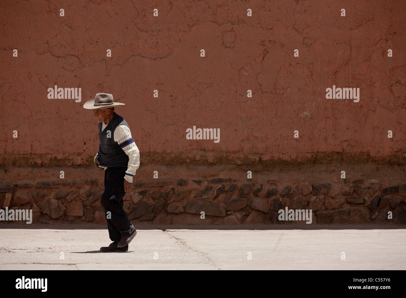 Un antiguo hombre peruano camina pegar una pared en la ciudad rural de Lampa. Lampa es cerca de Puno y Juliaca. Foto de stock