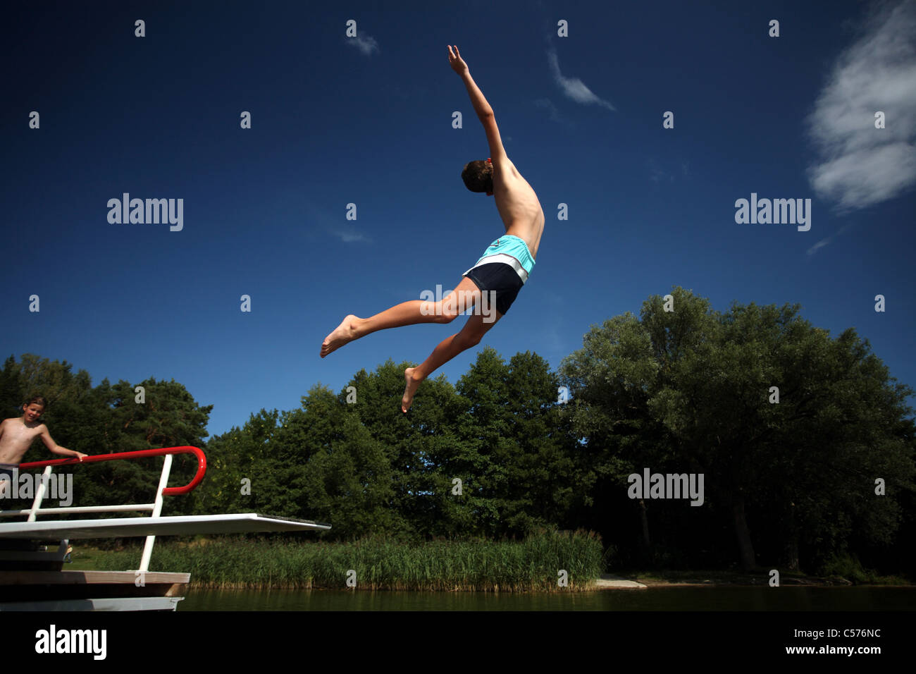 Un muchacho saltando al agua desde un trampolín Foto de stock
