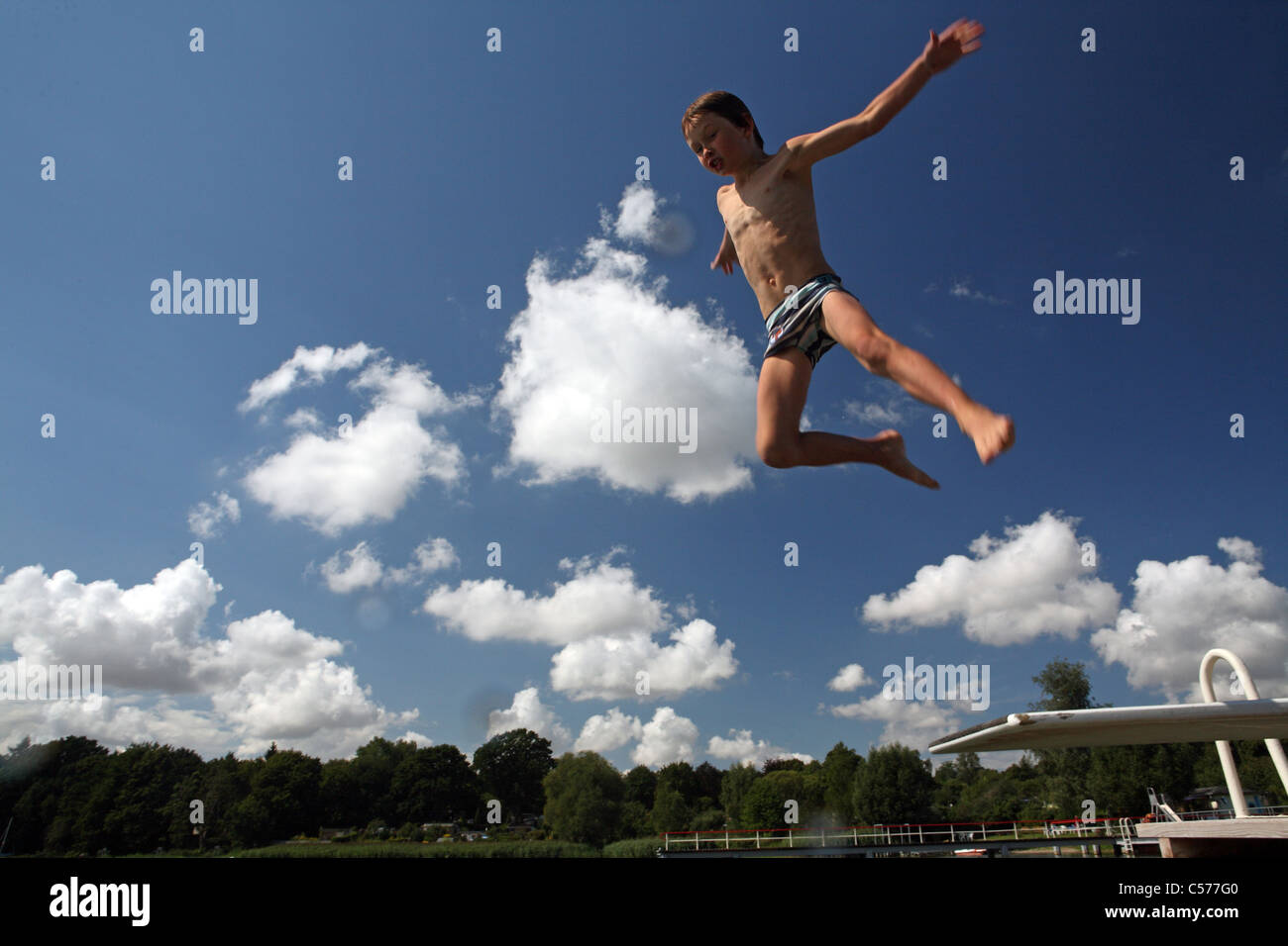 Un muchacho saltando al agua desde un trampolín Foto de stock