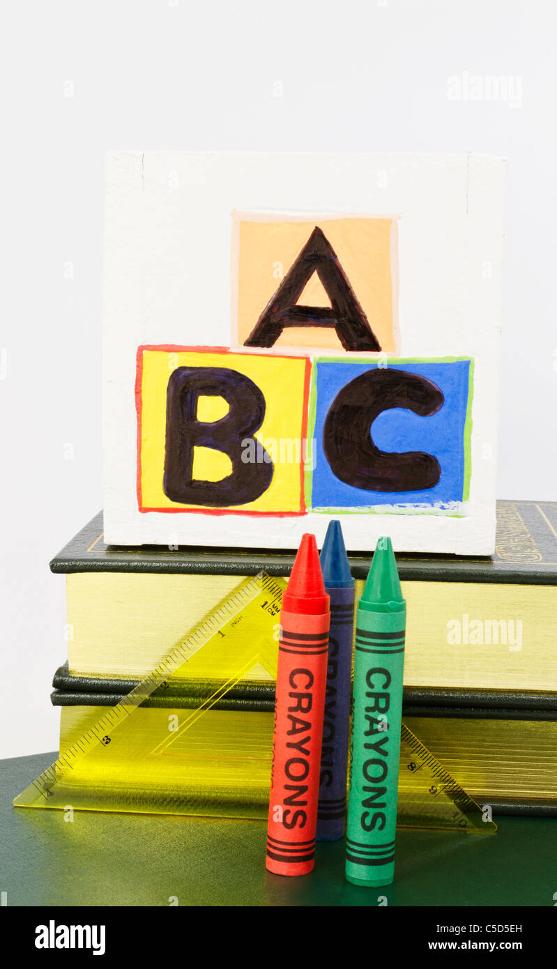 Caja de madera con letras ABC se sitúa en la parte superior de libros con  las herramientas de la escuela primaria de triángulo regla y 3 lápices de  colores en la parte