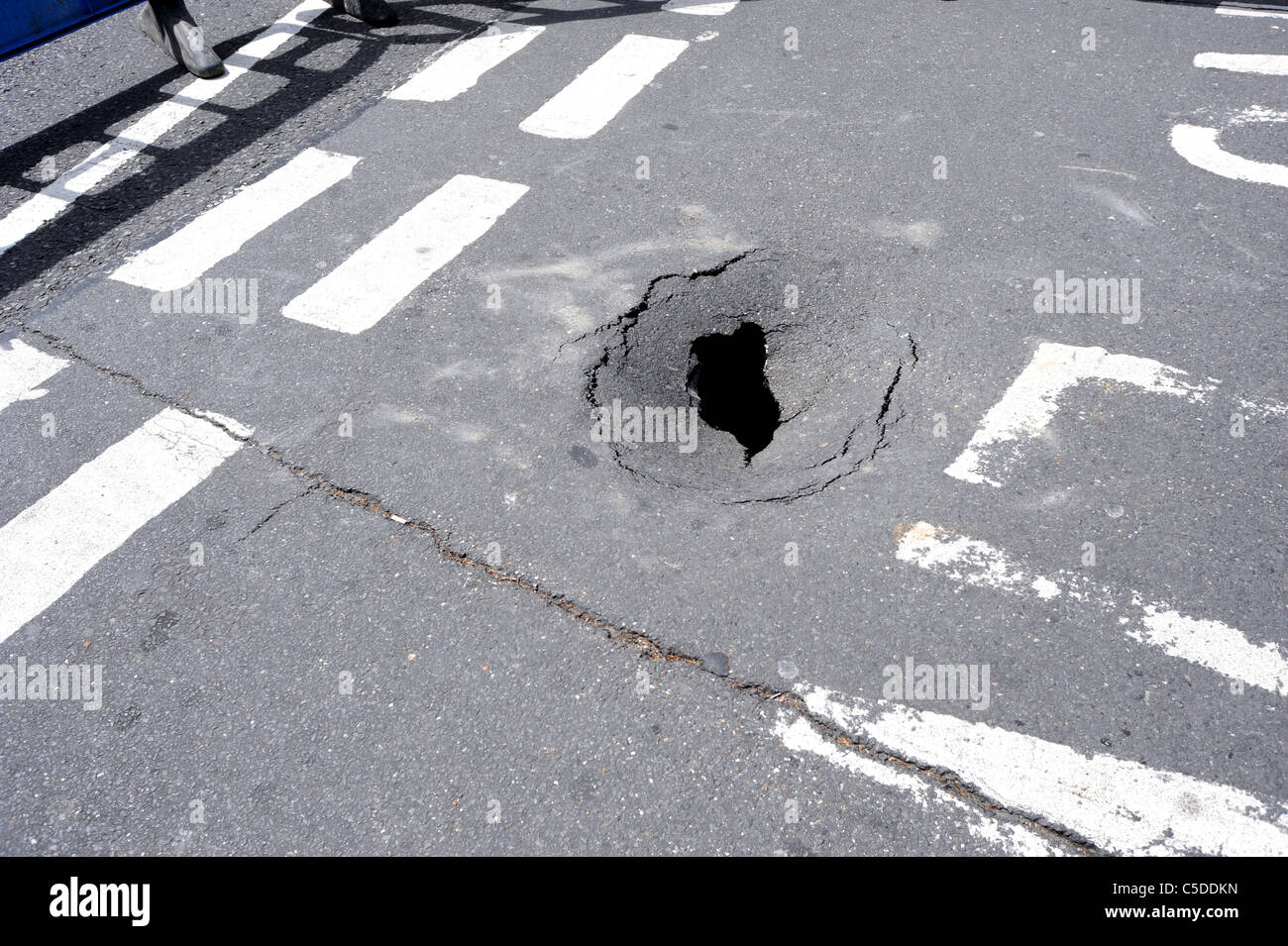 Una barrera de seguridad se coloca alrededor de un agujero que apareció de repente en una calle transitada en Hove Foto de stock