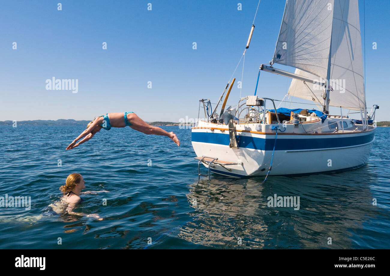 Hembra saltar al agua desde un barco contra el cielo azul claro Foto de stock