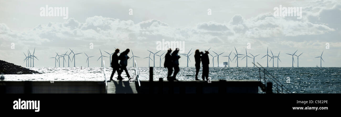Foto Panorámica de la gente en silueta de un lago con embarcadero de aerogeneradores en el fondo Foto de stock