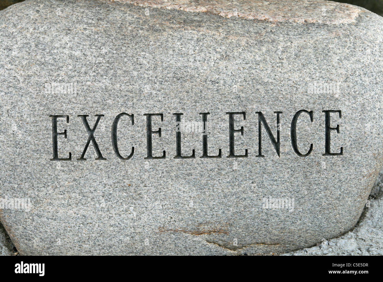 La palabra excelencia tallada en una piedra de guijarros de granito Foto de stock