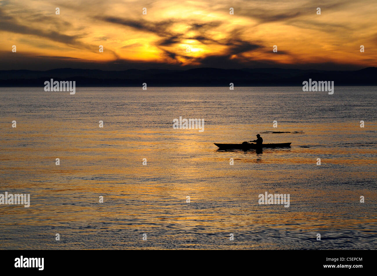 Hombre solitario kayak palas de Puget Sound, la Isla San Juan al atardecer Foto de stock