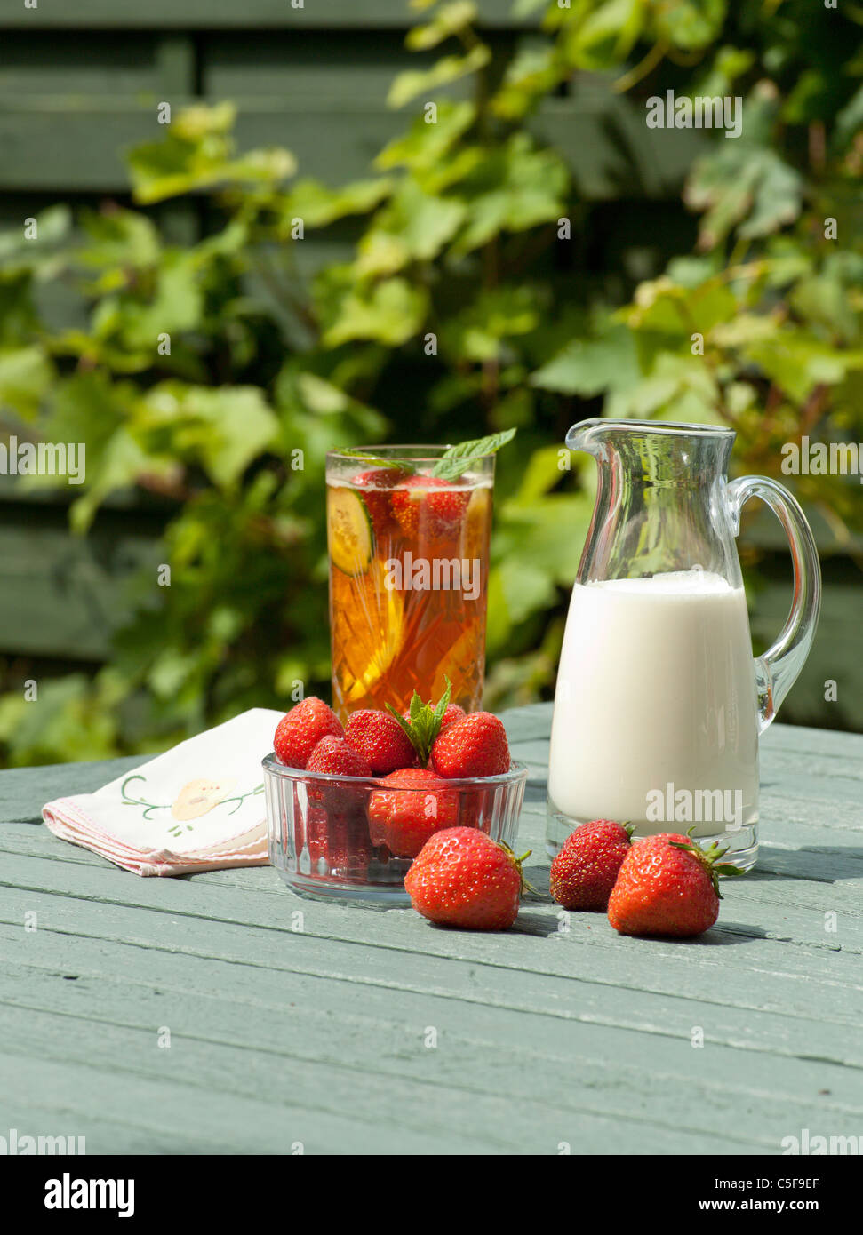 PIMMS y fresas con crema en el jardín de verano UK Foto de stock