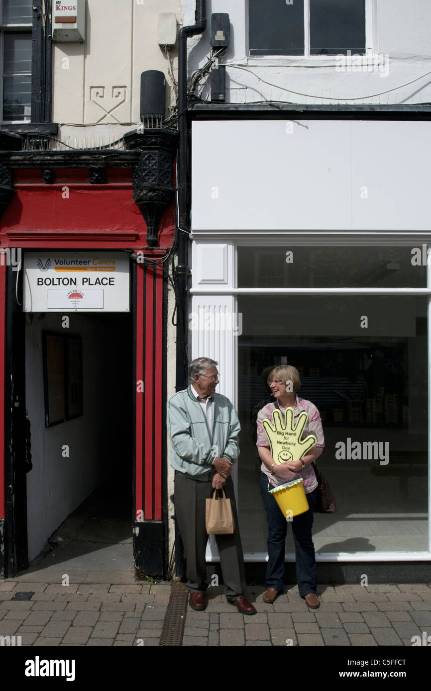 Dos personas caridad coleccionistas chateando en una calle de Newbury Berkshire Inglaterra Foto de stock
