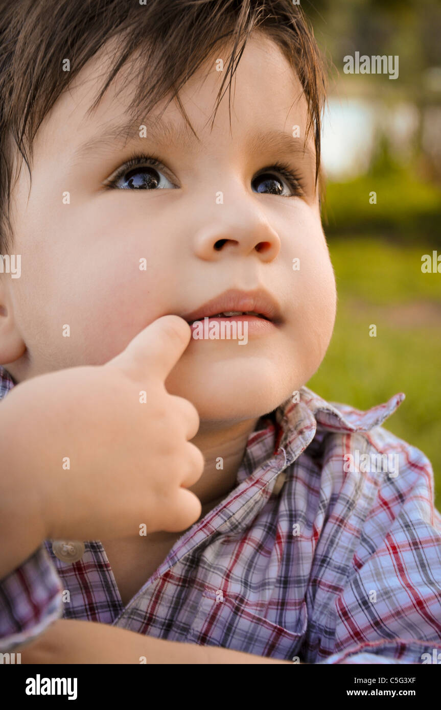 Close-up retrato de un niño pequeño mientras él viene con la siguiente gran idea, mostrando un pensamiento expresión en su rostro. Foto de stock