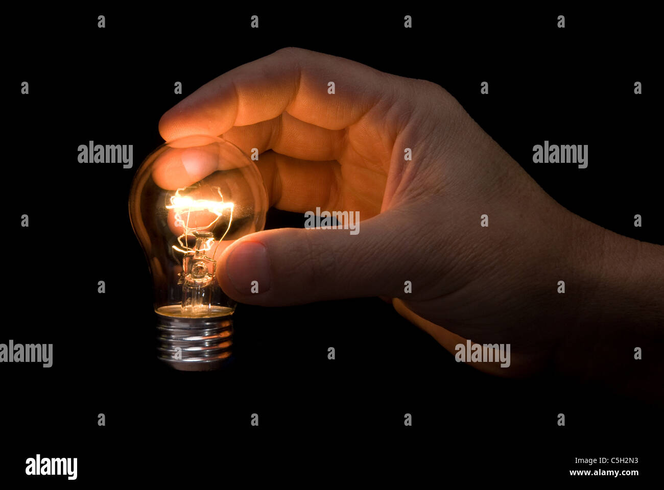 Una bombilla iluminada real sostenido en la mano de un ingeniero promovió la generación de ideas y pensamiento creativo inferencias. Foto de stock