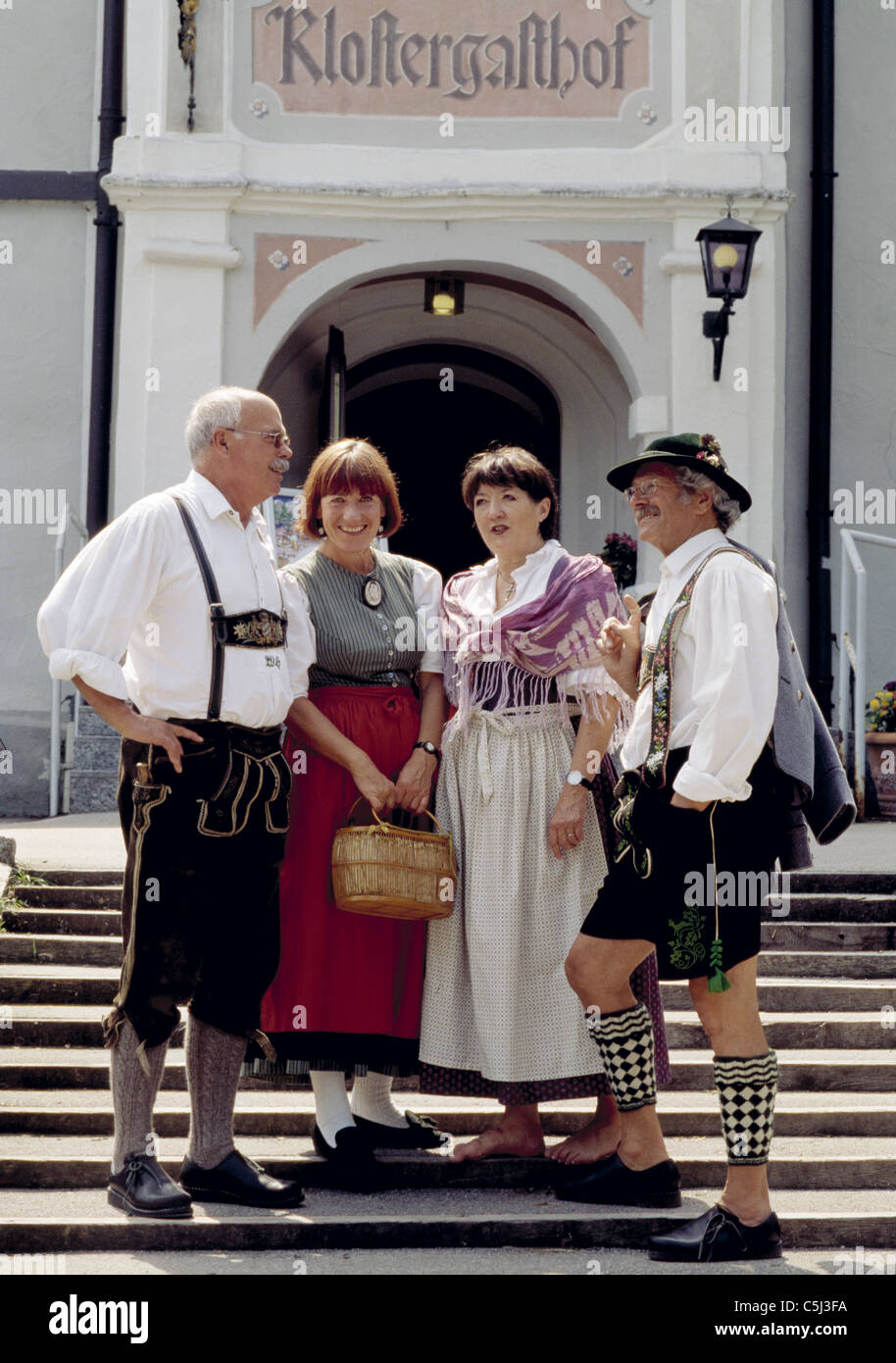El grupo de cuatro bávaros en traje tradicional de pie en pasos de guest house Foto de stock