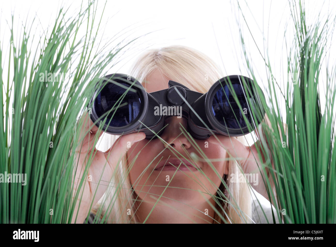 Joven Mujer rubia con binoculares tumbado en la hierba Foto de stock
