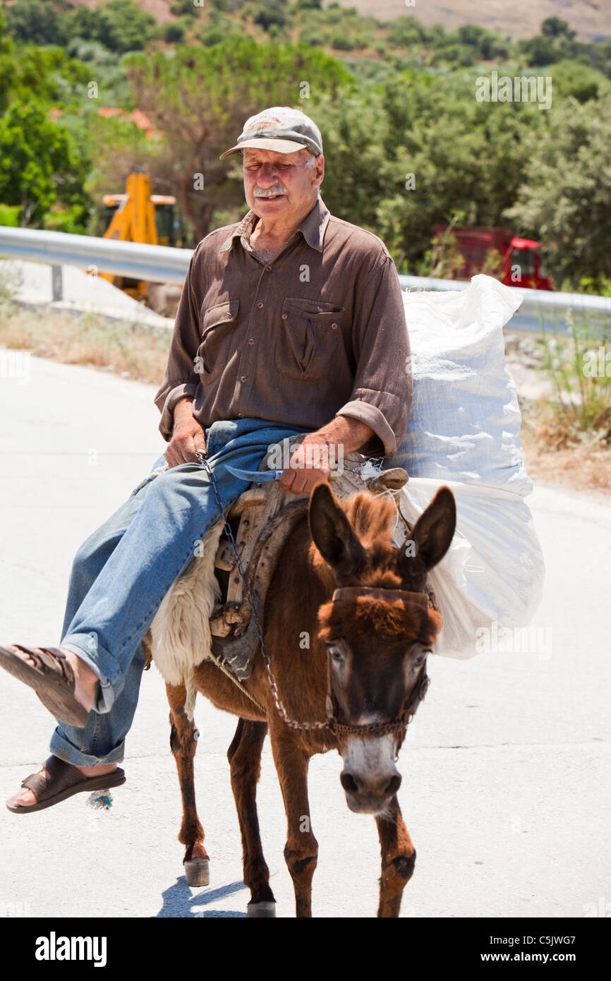 Un viejo agricultor griego con una forma tradicional de transporte, el burro, cerca de Skala Eresou, Lesbos, Grecia. Foto de stock