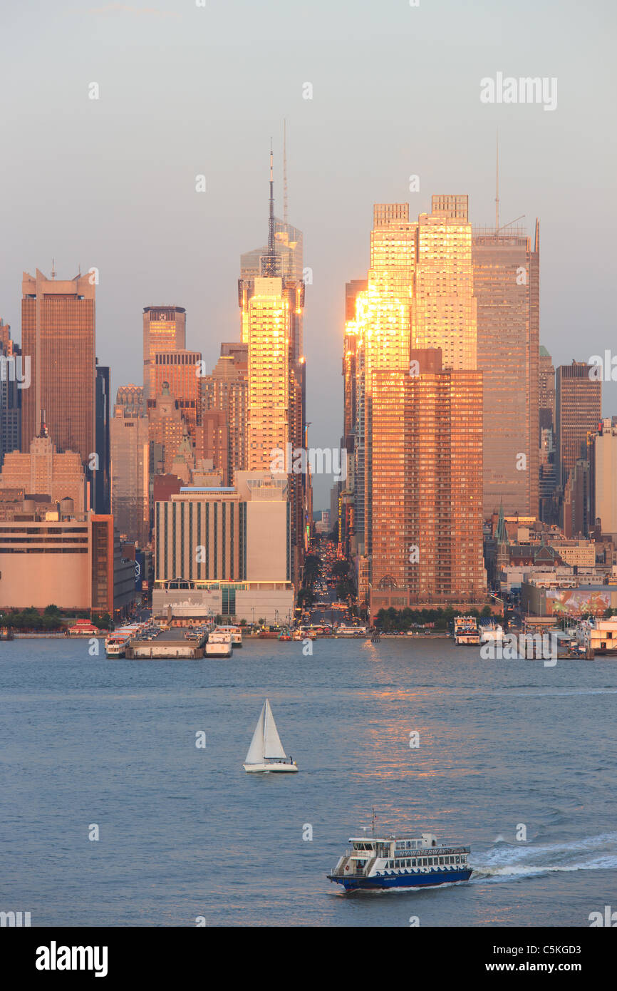 La puesta del sol se refleja en las ventanas de rascacielos de Manhattan en la calle 42 como se ve en el río Hudson desde Nueva Jersey Foto de stock
