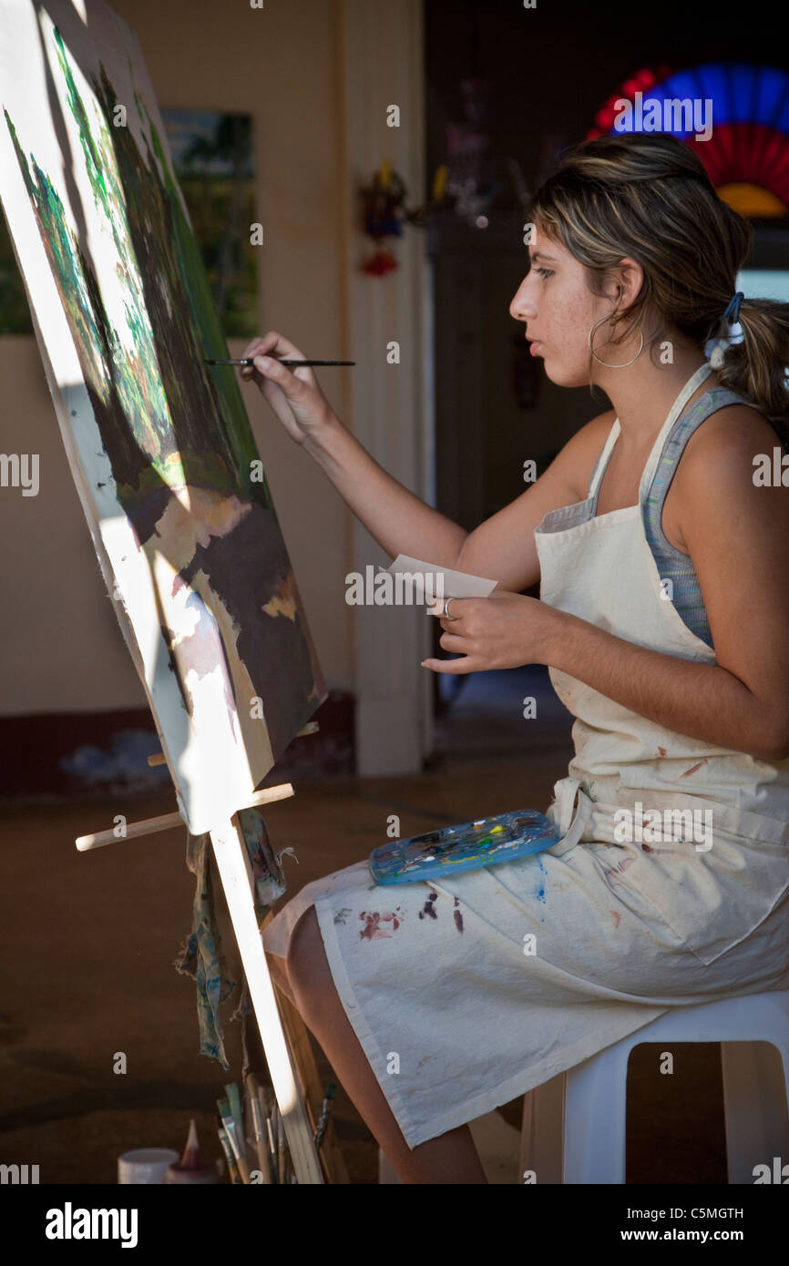 Cuba, Trinidad. Mujer joven en su pintura de caballete. Foto de stock