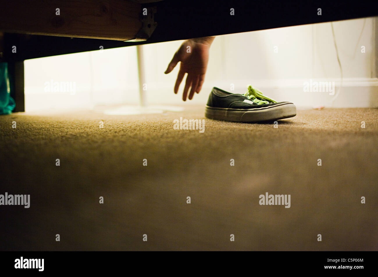 Muchacho recogiendo zapatos de bajo la cama Fotografía de stock - Alamy