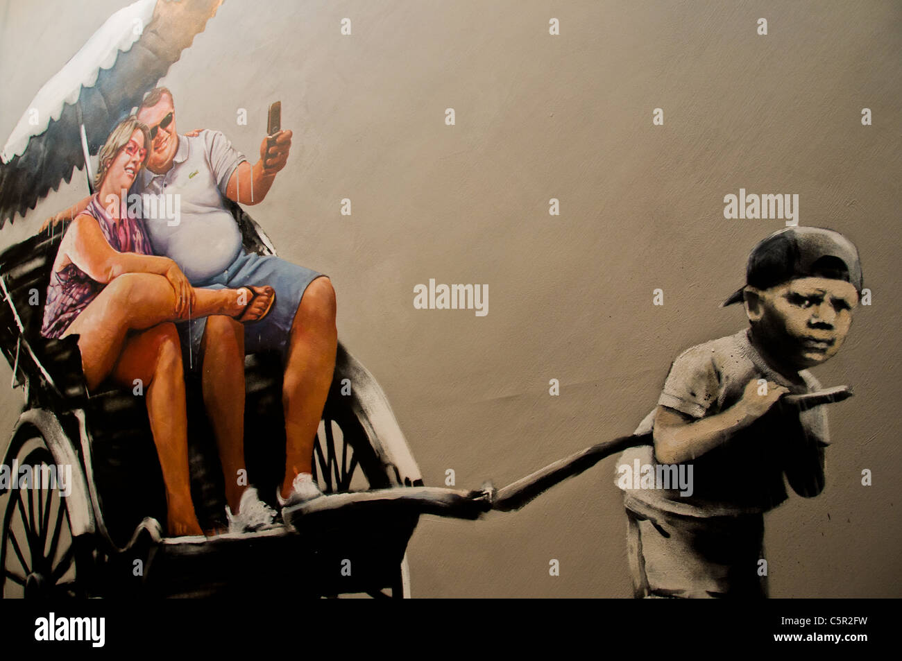 Banksy imagen del niño pequeño del tercer mundo tirando 2 grandes turistas occidentales en un rickshaw Foto de stock