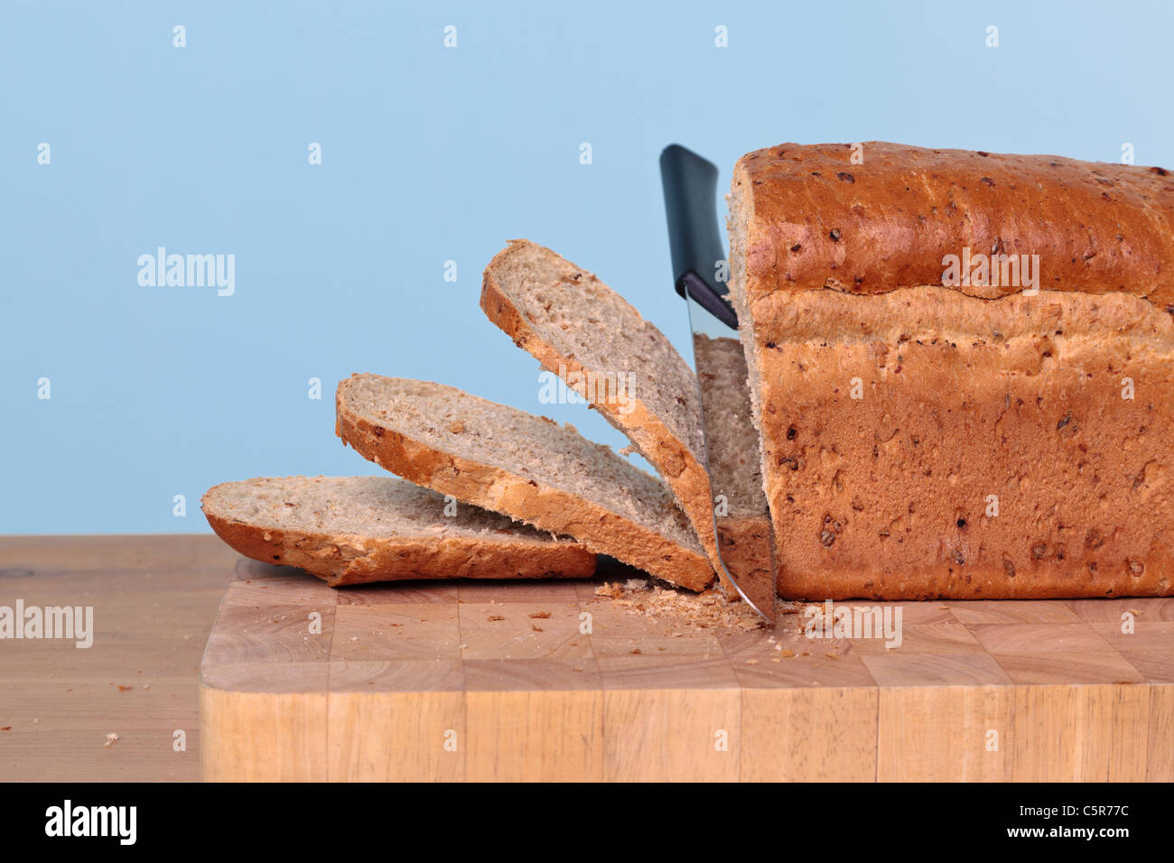 Foto de una hogaza de pan integrales ser cortado en rodajas con un cuchillo. Foto de stock