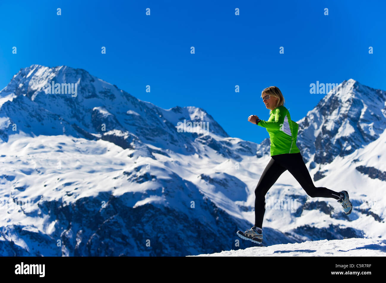Una mujer correr a través de nevadas montañas alpinas. Foto de stock