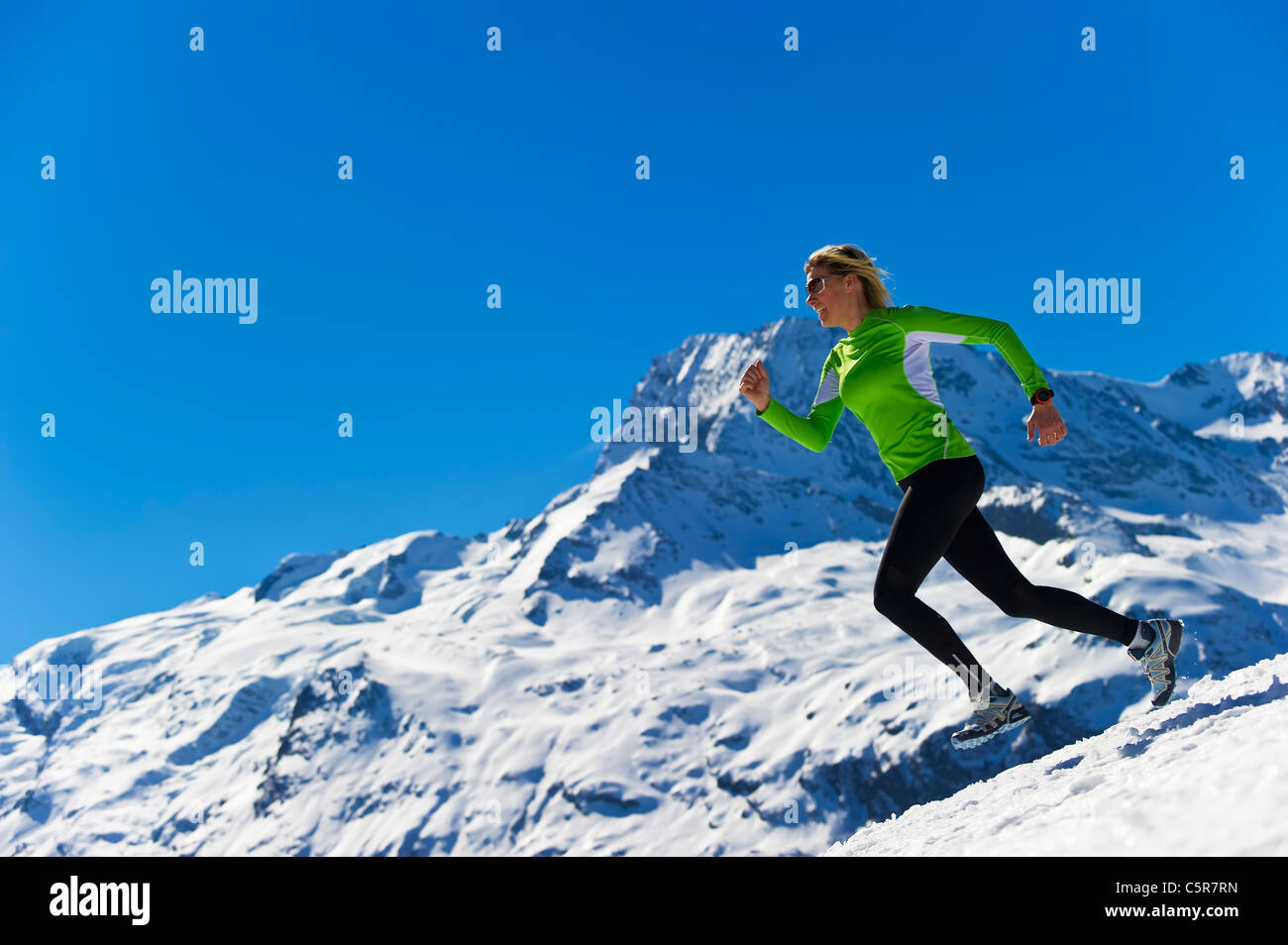 Una mujer jogging en altas montañas alpinas nevadas. Foto de stock