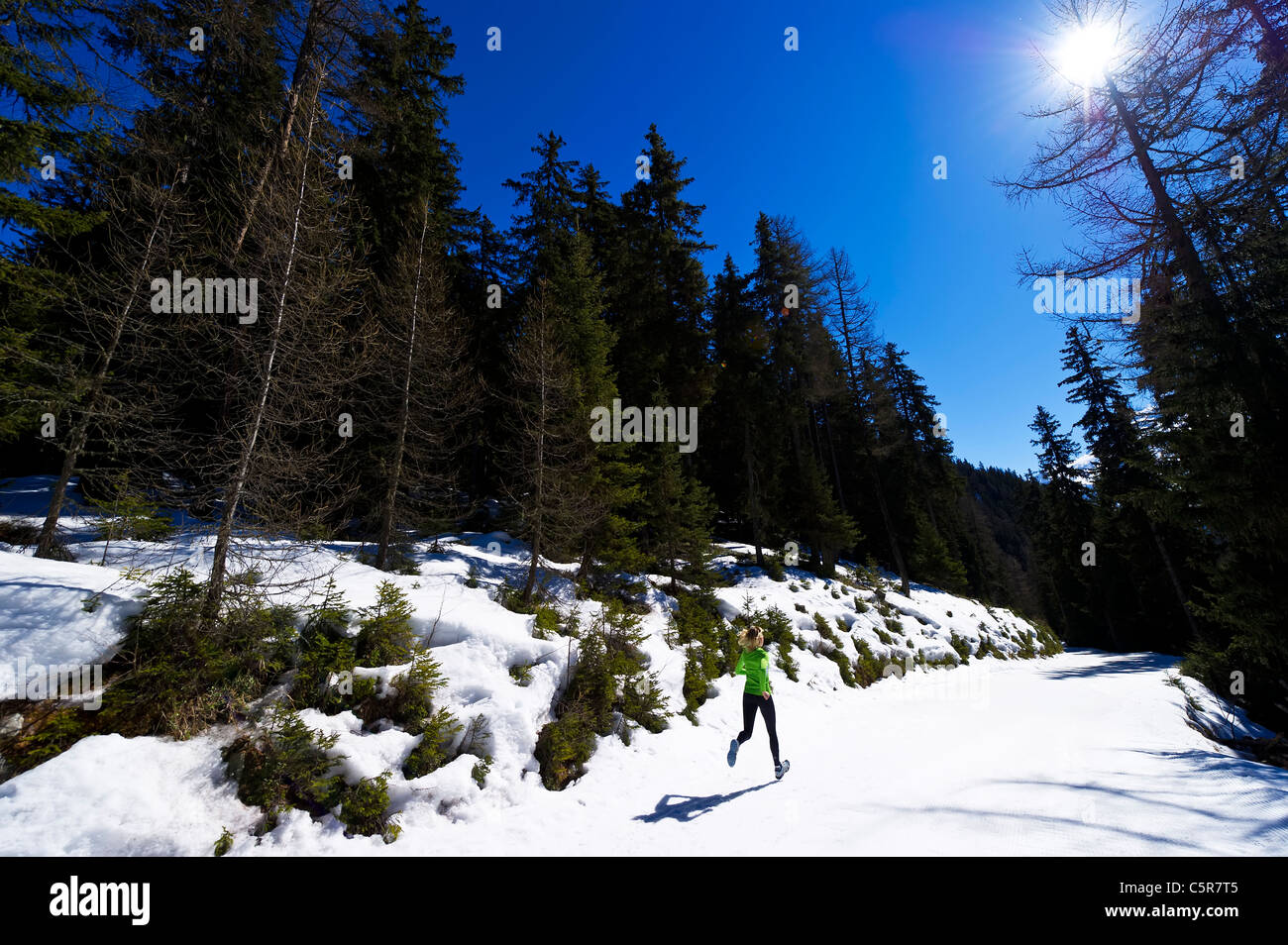 Una mujer correr a través de un bosque de montaña nevada. Foto de stock