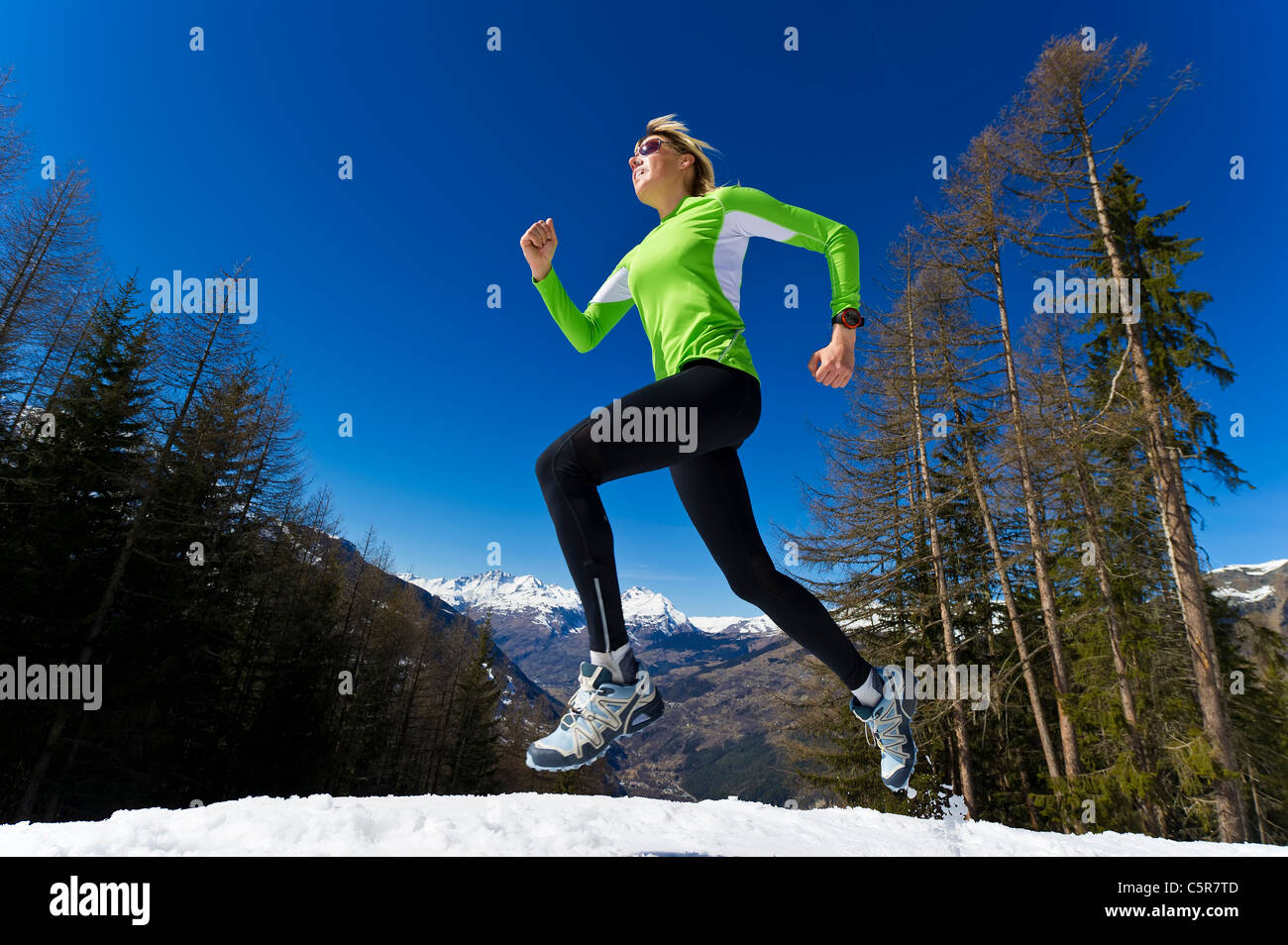 Una mujer correr a través de invierno con nieve de las montañas. Foto de stock