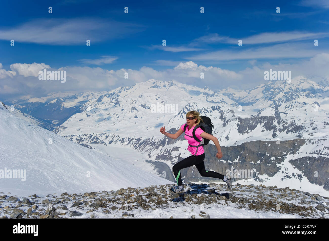 Una mujer corriendo rápidamente a través de montañas nevadas. Foto de stock