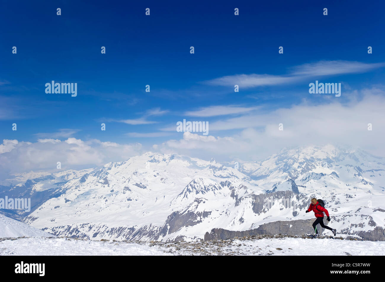 Una mujer corriendo en alta montaña picos nevados. Foto de stock