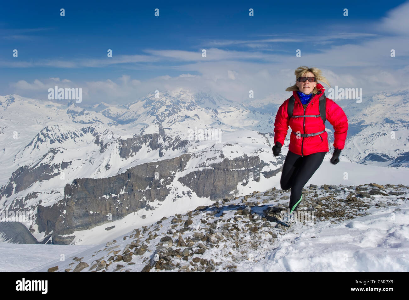 Mujer correr por los altos picos nevados. Foto de stock