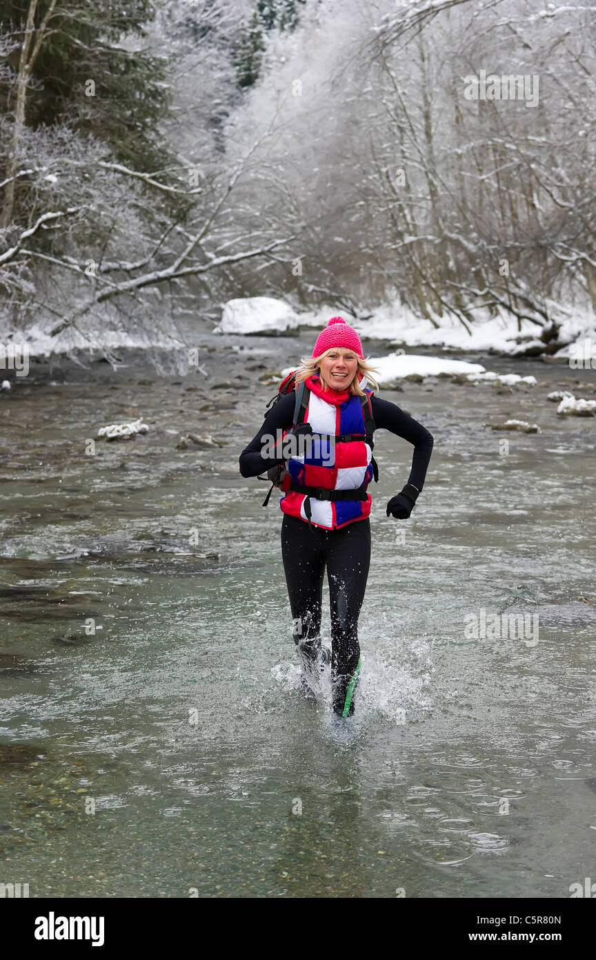 Un corredor ignora el agua fría y disfruta de un lecho de río nevado cruce. Foto de stock