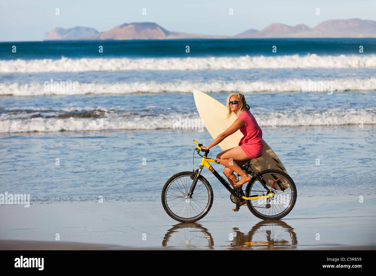 Surfer montando en bicicleta de montaña a lo largo de los océanos edge. Foto de stock