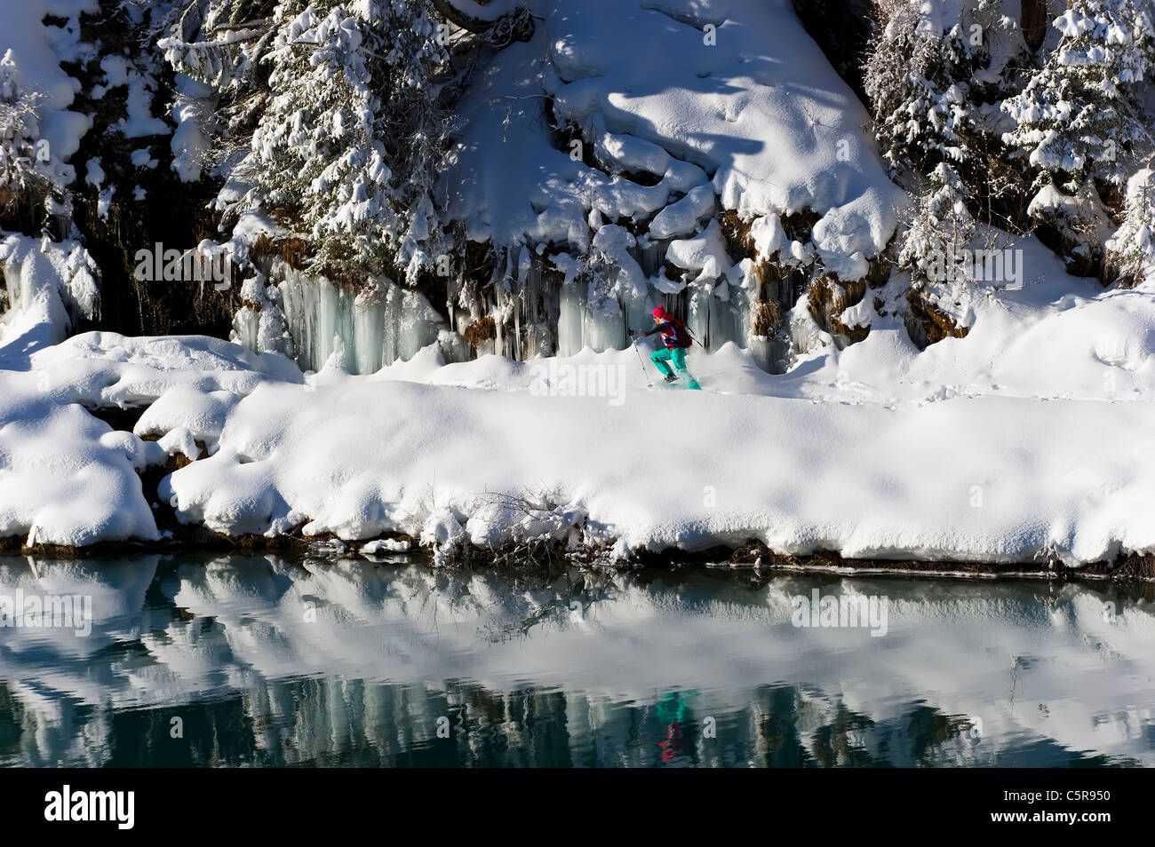Una mujer raquetas de nieve junto a un lago alpino de montaña, impresionantes. Foto de stock