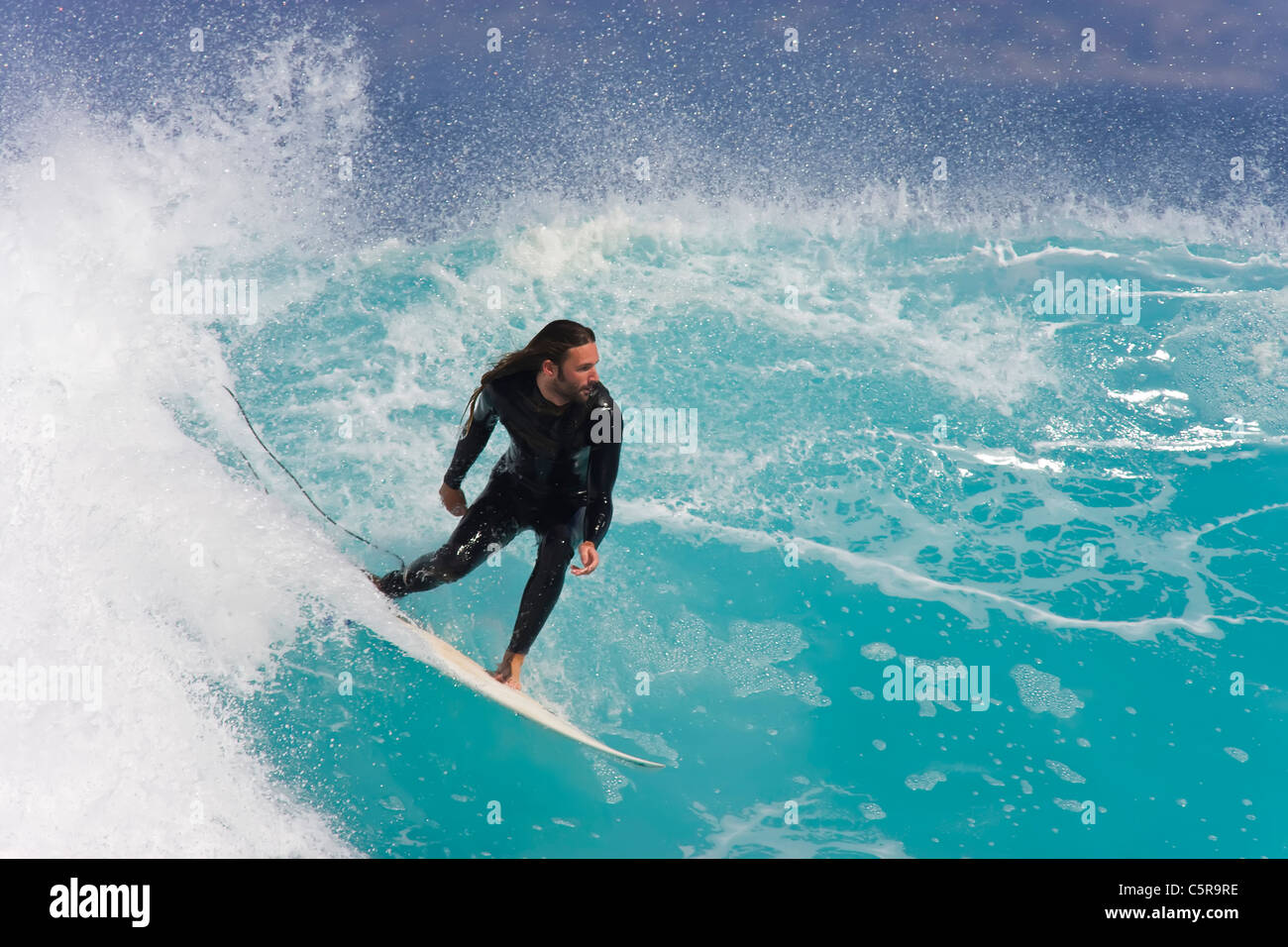 Un surfista cabalga una impresionante ola del océano azul celeste. Foto de stock