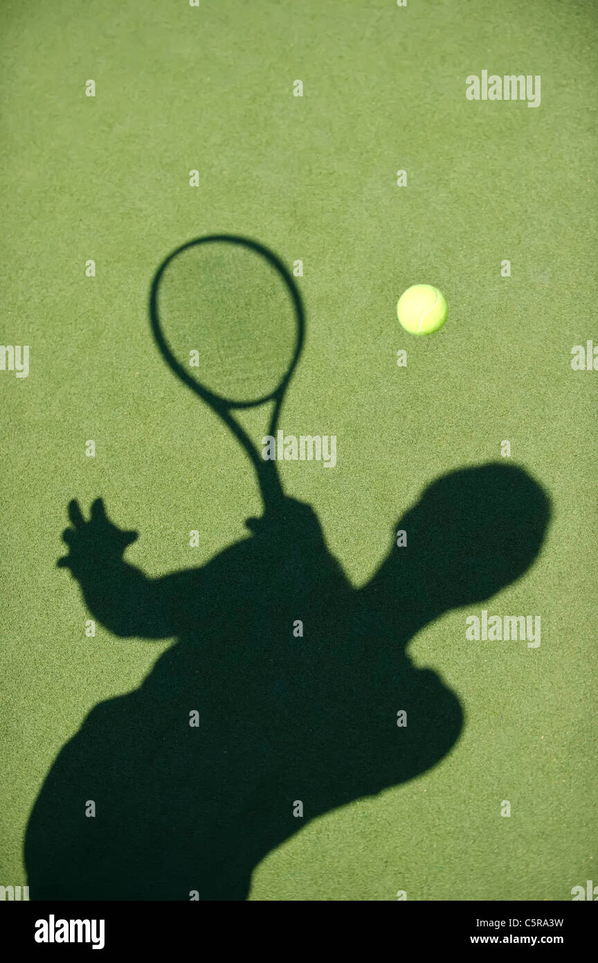 Un jugador de tenis silueta devuelve el balón. Foto de stock