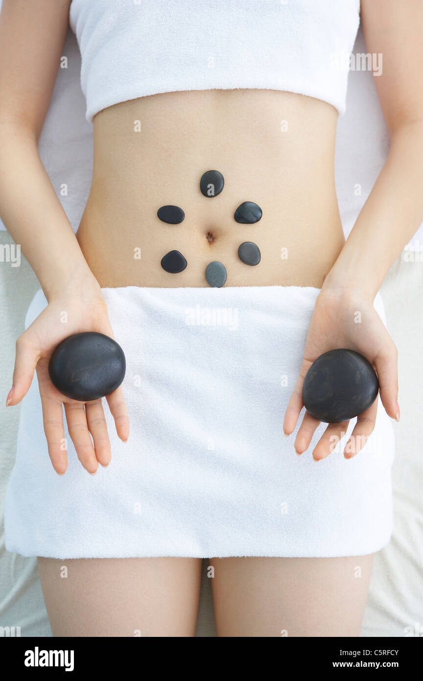 Una mujer recibiendo terapia de masaje con piedras calientes en la sección intermedia Foto de stock
