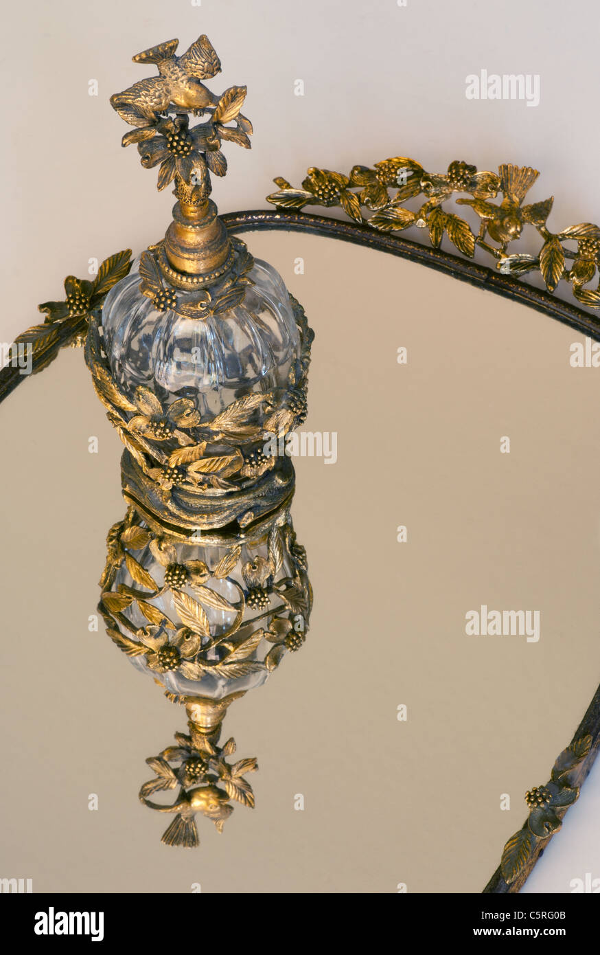 Conjunto de tocador: Espejo de oro vintage y botella de perfume a juego con topper de pájaro Foto de stock