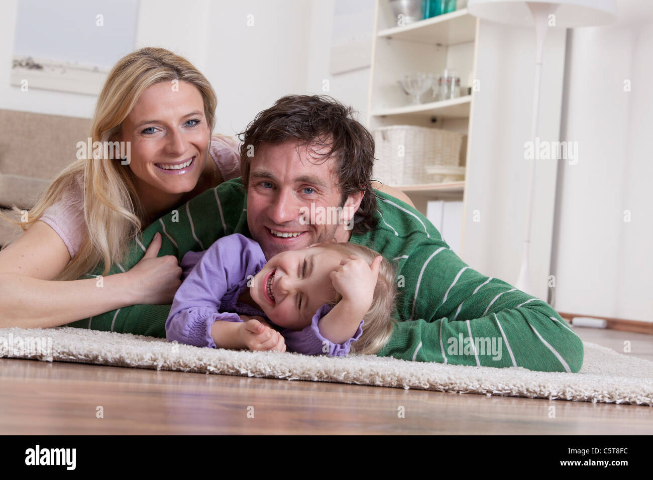 Alemania, Baviera, Munich, Familia acostado sobre una alfombra, sonriendo Foto de stock
